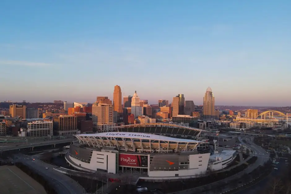 Downtown Cincinnati in warm evening light behind Paycor Stadium on the Ohio River.