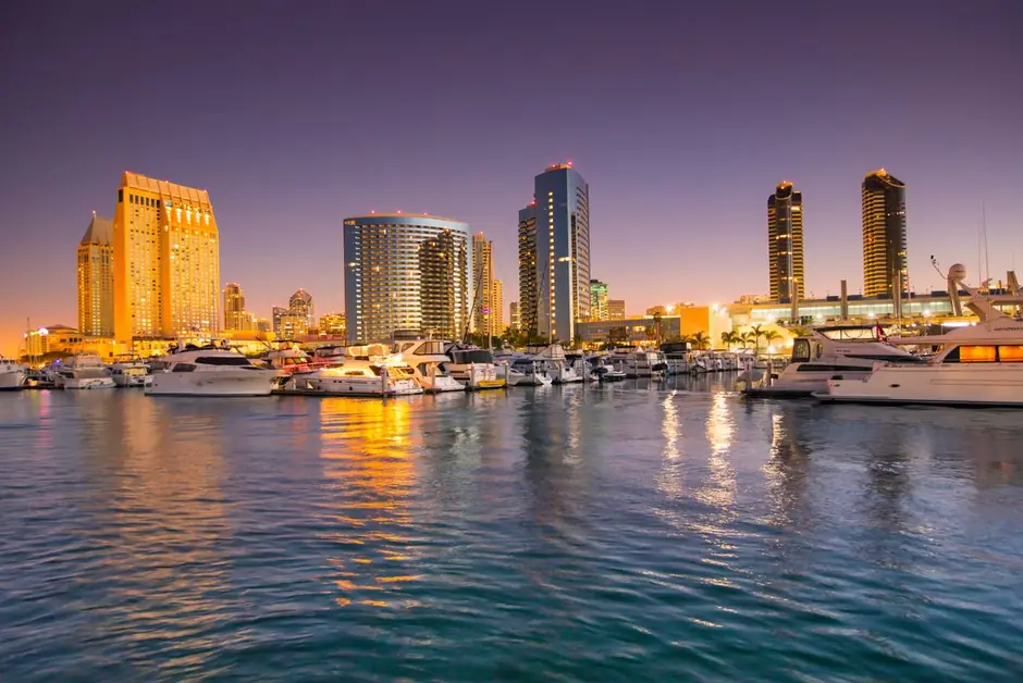The towers of downtown San Diego glowing at dusk over the yachts of the bay marina.