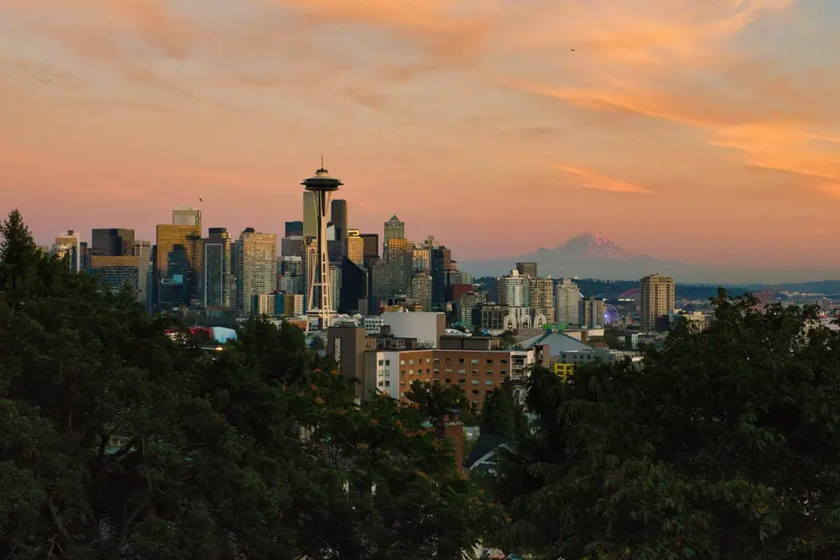 Stunning view of Seattle skyline at sunset featuring Space Needle and Mount Rainier.